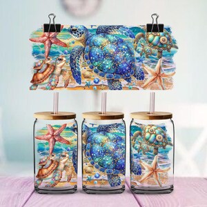 May include: Three glass tumblers with bamboo lids and straws, each featuring a colourful sea turtle design. The design includes starfish, sand, and ocean elements. A matching sign with the same design is clipped above.