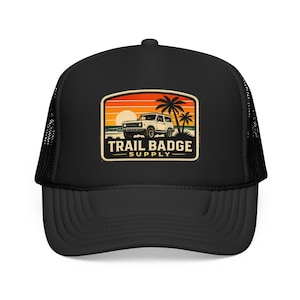 May include: Black trucker cap with a mesh back and a curved peak. The front displays a rectangular patch with a sunset scene, palm trees, and a white off-road vehicle. The text "TRAIL BADGE SUPPLY" is below the image.