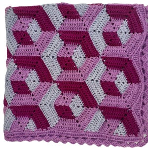 May include: A handmade crochet blanket featuring a geometric pattern in shades of purple, magenta, and gray. The blanket has a scalloped edge and is made of soft yarn. This cozy blanket is perfect for snuggling.
