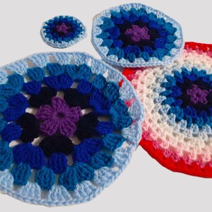 May include: A selection of handmade crochet items in different sizes and colours. The items have a circular design with a central flower motif. Colours include shades of blue, purple, red, and white. The crochet work appears to be tightly woven.