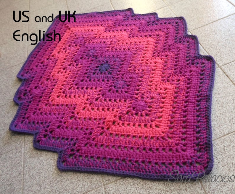 May include: A crocheted square blanket with a gradient of pink, purple, and dark purple. The blanket has a scalloped edge and is made with a textured stitch.