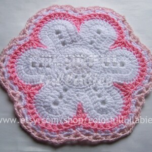 May include: A white crocheted flower with a pink border. The flower has a five-petal design and is made with a delicate stitch.