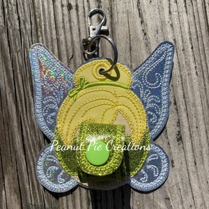May include: A yellow and green fairy-themed key chain with a glitter finish. The key chain has a small green button and the text "Peanut Pie Creations".