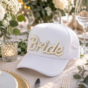 a table setting with a white hat with the word "Bride" on it, surrounded by various tableware and floral arrangements.