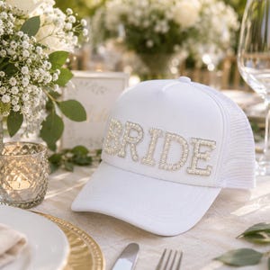 a table setting with a white hat with the word "BRIDE" on it, surrounded by various tableware items such as plates, glasses, and a vase.