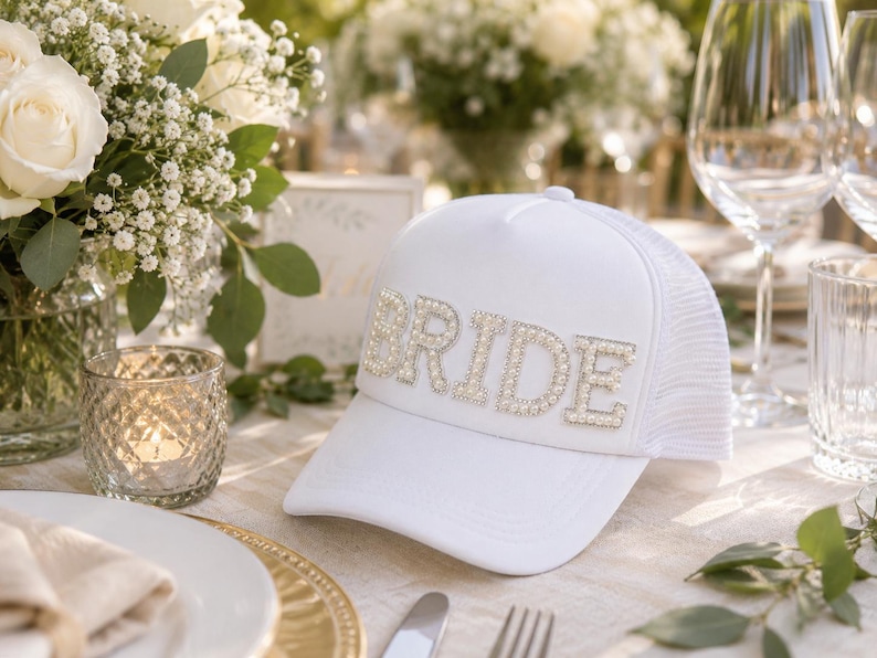 a table setting with a white hat with the word "BRIDE" on it, surrounded by various tableware items such as plates, glasses, and a vase.