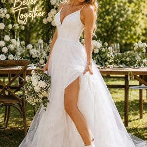 A woman in a white wedding dress and a white hat stands in a garden, holding a bouquet of white flowers and smiling.