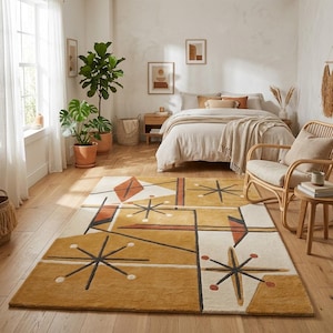 May include: A rectangular area rug featuring a geometric pattern with mustard yellow, cream, and burnt orange sections. The design includes black starburst motifs, thin black lines, and solid shapes arranged in an abstract composition on the floor.