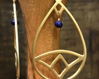 May include: Gold earrings with a geometric teardrop design and blue gemstone accents.