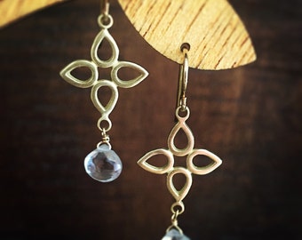 May include: Gold earrings with a delicate cross design and clear teardrop-shaped crystals hanging from the bottom.