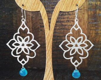 May include: Silver filigree earrings with a turquoise gemstone dangle. The earrings feature a delicate floral design.