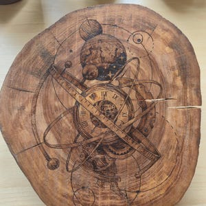 May include: A round, wooden decorative piece with a detailed, etched design of an astronomical clock and celestial bodies. The wood has a natural, warm brown tone, with the etched design in a darker brown. The design includes Roman numerals and various astronomical elements.