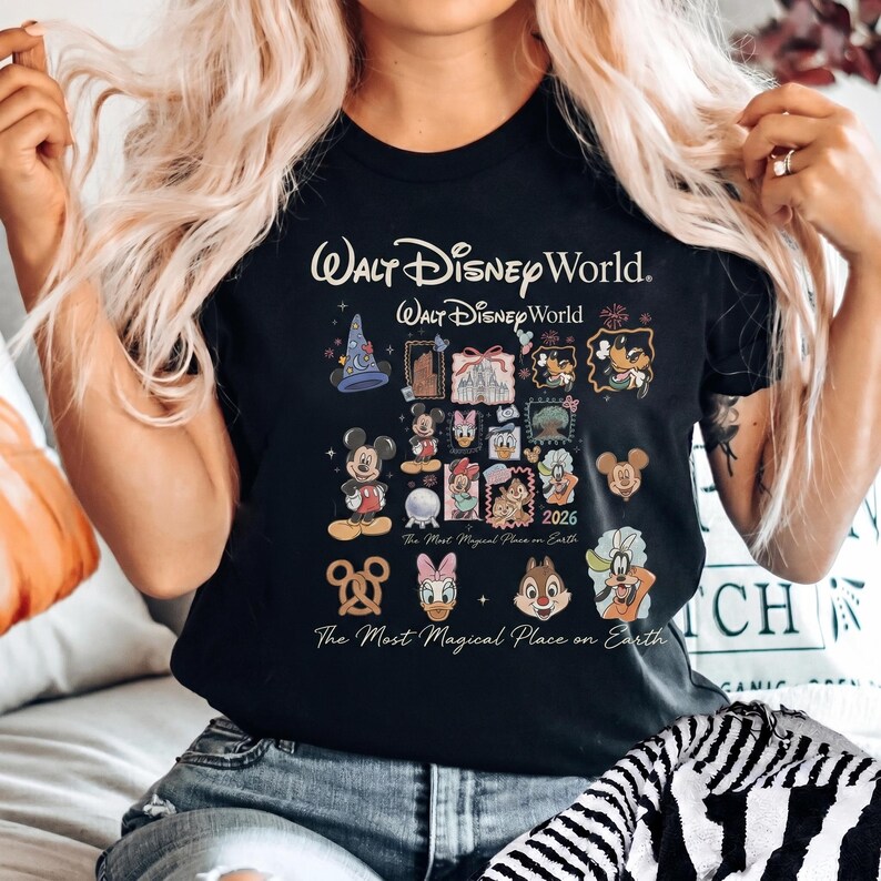 Woman wearing black t-shirt featuring vibrant Disneyworld character collage and magical place on earth script.