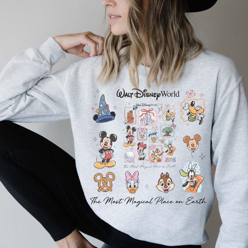 Woman wearing ash grey crewneck with vintage Mickey and friends postage stamp design in a cozy setting.