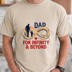 Puede incluir: Camiseta beige con un diseño gráfico que presenta la palabra "DAD" sobre un símbolo de infinito con las palabras "UNCONDITIONAL LOVE". Debajo del símbolo, el texto dice "FOR INFINITY & BEYOND". El diseño incluye siluetas de un padre y un hijo.