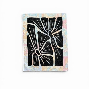 Peut inclure: Une pièce textile rectangulaire présentant un motif floral abstrait noir audacieux avec des pétales allongés, centré sur un fond de couleurs pastel douces et atténuées, incluant du rose, du bleu et du jaune en motif géométrique.