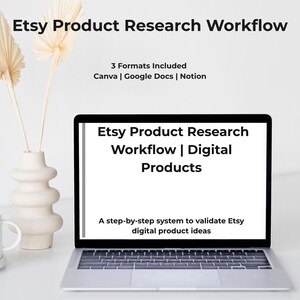 May include: A laptop displays "Etsy Product Research Workflow | Digital Products." The screen shows a step-by-step system to validate Etsy digital product ideas. A white mug, vase with dried flowers, and a laptop are on a white surface.