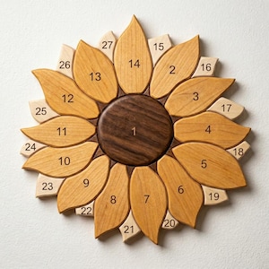 May include: Wooden sunflower wall art with a dark brown center and numbered petals in varying shades of light brown and tan. The sunflower is made of wood and has 27 petals. The numbers 1-27 are visible on the petals.