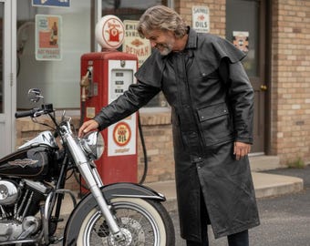 May include: A long black leather duster coat featuring a wide shoulder cape, a high collar, long sleeves, and two large front flap pockets. The coat has a button-down front closure and extends to the mid-calf, providing full-length coverage.