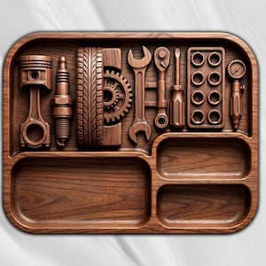 Op de afbeelding: Een rechthoekig houten dienblad met afgeronde hoeken voorzien van uitgesneden motieven van auto- en mechanisch gereedschap. Het bovenste gedeelte bevat een zuiger, bougie, band, tandwiel, moersleutel, ratel, schroevendraaier, boutplaat en manometer. Twee lege vakken eronder.