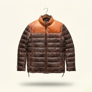 Puede incluir: Una chaqueta acolchada con un diseño bicolor que presenta un canesú superior en tono beige tipo cuero y un cuerpo inferior en color marrón oscuro con acabado desgastado. Incluye cremallera central, cuello alzado y dos bolsillos laterales.