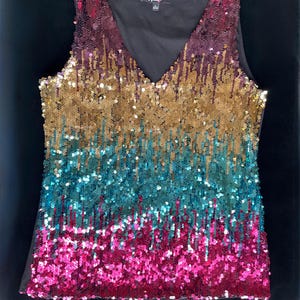May include: A sleeveless top with a V-neckline, covered in cascading sequins. The sequins transition from red to gold, teal, and pink. The top has a black lining and a tag with the brand name.