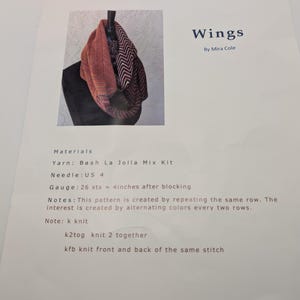 May include: A printed knitting pattern titled Wings by Mira Cole, featuring a photograph of a cowl with a chevron pattern in orange, black, and white. The document lists materials, US 4 needle size, a gauge of 26 stitches per 4 inches, and knitting abbreviations.
