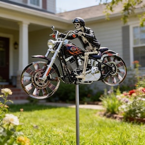 Puede incluir: Decoración de jardín de metal que representa un esqueleto montado en una motocicleta. El esqueleto lleva un casco y una chaqueta. La motocicleta es negra con llamas naranjas y detalles cromados. Las ruedas tienen un diseño de radios único.