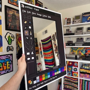 May include: A large framed artwork mimicking the Windows Paint interface, with a black frame and a toolbar of icons. The text "untitled - Paint" and menu options are displayed. The artwork reflects a room with colourful textiles and a rainbow-striped hanging.