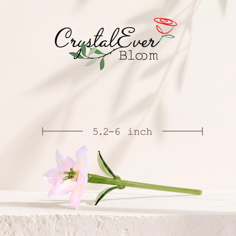 Puede incluir: Una flor de lirio de cristal con p&eacute;talos de color rosa p&aacute;lido y blanco, y un tallo verde con hojas. El texto CrystalEver Bloom aparece arriba con un icono de rosa roja. Una l&iacute;nea de medici&oacute;n indica una longitud de 13,2-15,2 cm.