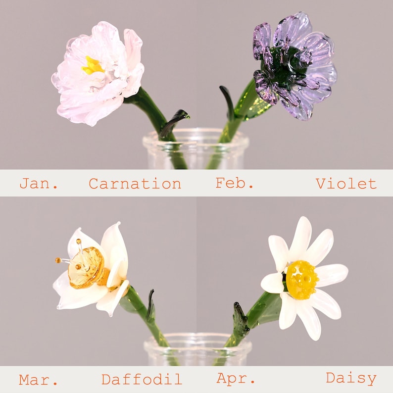Puede incluir: Cuatro flores de vidrio para los meses de nacimiento: un clavel rosa p&aacute;lido para ene., una violeta morada para feb., un narciso blanco con centro amarillo para mar., y una margarita blanca con centro amarillo para abr., con tallos verdes.