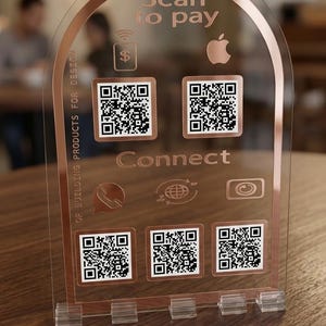 May include: Clear acrylic sign with rose gold accents. The sign features the text "Scan to pay" and "Connect", along with multiple QR codes and icons. The sign is designed for building products.