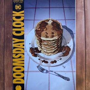 May include: A comic book cover for "Doomsday Clock" No. 4 of 12, featuring a stack of pancakes with chocolate syrup on a white plate. The DC Comics logo is visible, along with the text "MAY 2018". A silver fork rests on the table.