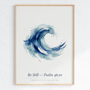 Può includere: Una stampa artistica da parete incorniciata con un dipinto ad acquerello di un'onda oceanica blu al centro. Sotto l'onda, il testo recita Be Still — Psalm 46:10 e Coastal Faith Collection. La stampa è racchiusa in una cornice di legno chiaro.