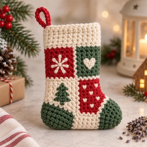 May include: A crocheted Christmas stocking featuring a patchwork design with cream, red, and dark green yarn. The pattern includes a white snowflake, a white heart, a green pine tree, and small white hearts on a red background with a loop.