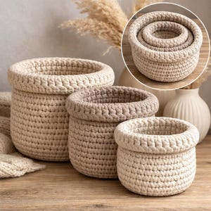 May include: A set of three round, cream-colored storage baskets made of thick, hand-crocheted cotton cord. The baskets feature a sturdy, textured weave with a thick, rolled-top rim. They are shown in varying sizes, nested together in a circular inset.