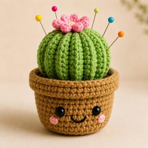 May include: A crocheted cactus pincushion in a brown pot with a smiling face. The green cactus features a pink flower on top and is decorated with five colorful sewing pins with yellow, red, green, blue, and orange spherical heads.
