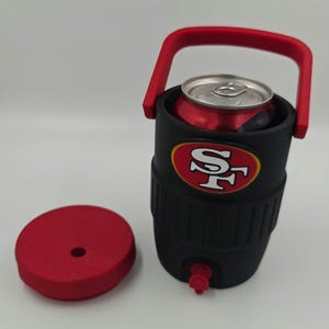 Puede incluir: Enfriador de bebidas aislado negro y rojo con asa y tapa rojas. El enfriador tiene un logotipo de los 49ers de San Francisco y contiene una lata roja. Tiene un peque&ntilde;o grifo rojo en la parte inferior.