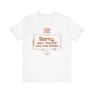 Op de afbeelding: Wit t-shirt met een oranje grafisch ontwerp. Het ontwerp bevat de tekst "Sorry, your request was rate-limited." en de merknaam "CLAWTHES". Het t-shirt heeft een ronde hals en korte mouwen.