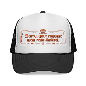 May include: A black and white trucker cap with a curved peak. The front panel features the orange text "Sorry, your request was rate-limited" within a rectangular design. The hat has a mesh back.