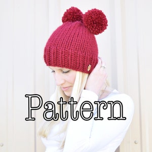 以下が含まれることがあります： 赤いニット帽に、2つのポンポンが付いている。シンプルなニットの編み方で、ゆったりとしたシルエット。帽子の下に「Pattern」という文字が大きく太字で書かれている。