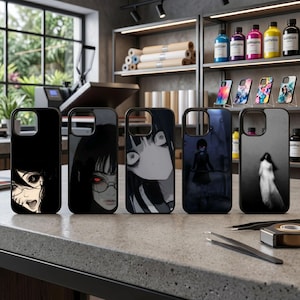 Pode incluir: Uma coleção de cinco capas de telefone pretas com designs exclusivos de personagens em estilo anime. As capas apresentam várias ilustrações em tons de cinza e cores, incluindo um personagem com olhos vermelhos e uma figura fantasmagórica. Exibidas em uma bancada cinza.