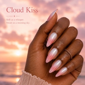 May include: A hand with long, almond-shaped nails featuring a gradient design, transitioning from a pearlescent white at the base to a soft pink at the tips. The nails are set against a sunset backdrop, with the text "Cloud Kiss".