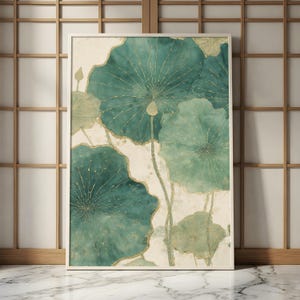 May include: A framed art print featuring a watercolor design of teal lotus leaves with gold accents. The artwork has a soft, textured appearance and is set against a cream-colored background. The frame is white.