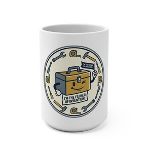 Puede incluir: Taza de cerámica blanca con un personaje de caja de herramientas de dibujos animados con una cara sonriente y el texto "I'M THE FATHER OF INVENTION". El diseño incluye varias herramientas alrededor de la caja de herramientas. Un regalo divertido.