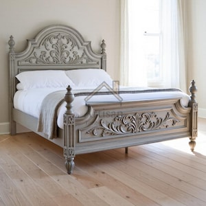 Könnte beinhalten: Ein grauer, verzierter Bettrahmen mit geschnitzten floralen Details an Kopf- und Fußteil. Das Bett ist aus Holz gefertigt und hat vier dekorative Pfosten. Weiße Bettwäsche und eine hellfarbige Decke.