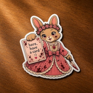 May include: A sticker featuring a cartoon bunny wearing a pink dress and flower crown, holding a card that says "here. have a card :) ". The bunny is also holding a knife. The sticker has a white border.