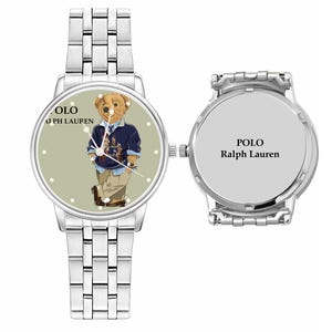 May include: Silver wristwatch featuring a light green face with a Polo Bear design. The bear wears a navy blue sweater and khaki pants. The watch has a silver band and the text "POLO Ralph Lauren".