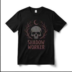 May include: A black short-sleeved t-shirt featuring a graphic print of a grey human skull centred between two bare tree branches. Above the skull is a crescent moon, and below the skull is the text SHADOW WORKER in a dark red font.