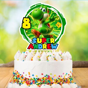 May include: A white frosted cake with colorful sprinkles and white frosting swirls. The cake is topped with a green and white Yoshi cake topper with the text "SUPER ANDREW" and the number 8.